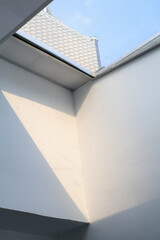Building a glass roof sky with bright sunshine. White wall interior with big window. Sunny day through shining house.