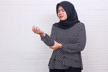 Female in hijab holding her arm. Arm pain and injury. Health care and medical concept.
