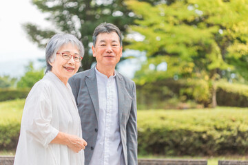 Obraz premium 公園を歩くシニア・高齢者夫婦（カメラ目線） 
