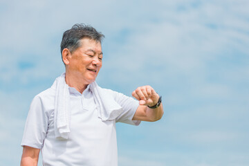 腕時計・活動量計を見ながら運動・トレーニング・ウォーキングする笑顔のシニア・高齢者男性