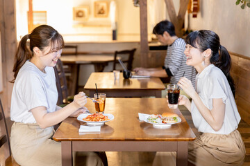 カフェ・レストラン・飲食店でランチをしながらおしゃべりする若いアジア人女性
