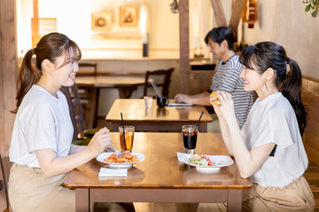 カフェ・レストラン・飲食店でランチをしながらおしゃべりする若いアジア人女性
