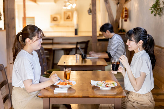カフェ・レストラン・飲食店でランチをしながらおしゃべりする若いアジア人女性
