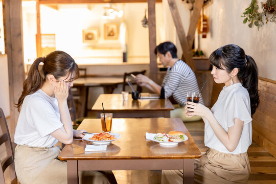 カフェでランチをしながら悩み相談を友達にする若いアジア人女性
