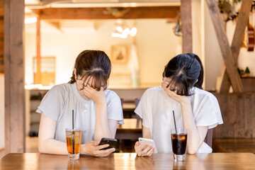 スマホを見て泣く・絶望するアジア人女性

