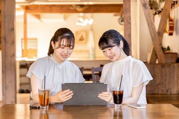 タブレットでネットショッピング・動画を友達と見るアジア人女性

