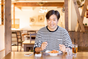 お昼休みにカフェやレストランでランチ・食事をするアジア人の男性
