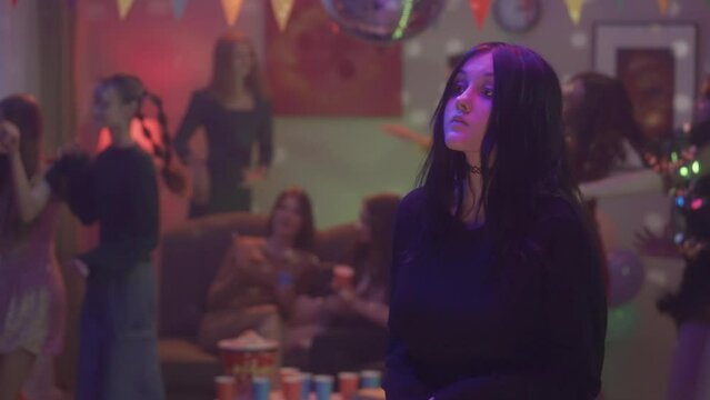 A goth girl in feeling awkward, lonely and uncomfortable at a party, slowly dancing and fixing her hair. The girl's friends are having fun and dancing. HDR BT2020 HLG Material.