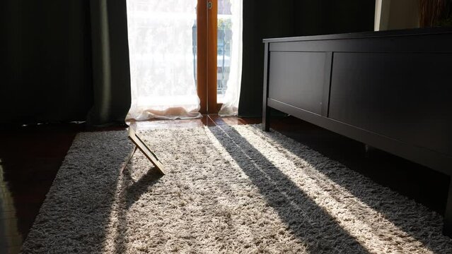 Sunlight shining passing through the window of bedroom in the dark with picture frame on the floor. No people in dark room.