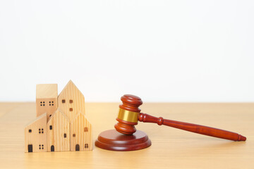 Real Estate Law, Home Insurance, property Tax, Auction and Bidding concepts. small toy house model with gavel justice hammer on desk in courthouse.