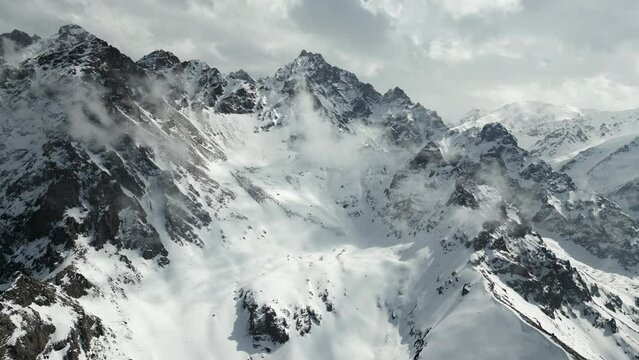 Aerial of the snow covered mountains near Shymbulak in Kazakhstan. Drone very slow dolly forward shot
