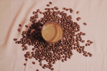 Cup of coffee with and coffee beans on peach color background. Creative layout. Breakfast concept. Top view, flat lay