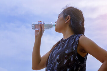 Silhouette of young woman runner with a bottle of water freshness after training outdoor workout.	
