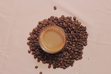 Cup of coffee with and coffee beans on peach color background. Creative layout. Breakfast concept. Top view, flat lay