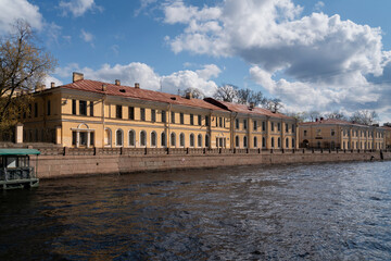 Fototapeta na wymiar View of the academic buildings of the A.I. Herzen Russian State Pedagogical University on the Moika River embankment on a sunny day, Saint Petersburg, Russia