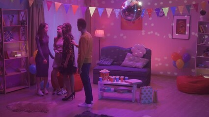 A guy at a house party approaches a group of girls and invites one of them to dance. The couple is dancing a dance under the gaze of the girl's girlfriends. Video 2 in 1. HDR BT2020 HLG Material.