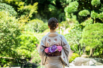 日本庭園の前で佇む着物を着た上品な女性の後ろ姿