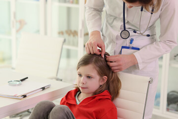 Therapist looks for insects in hair of little girl client