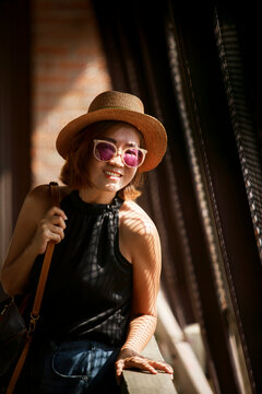 beautiful asian woman wearing straw hat toothy smiling with happiness standing in metal net wall