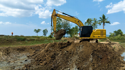 excavating soil into a dump truck to build a pond for store water for use in the dry season for...