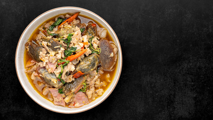 Pad Ka Prao Kai Yeow Ma, Thai food, basil stir fried century egg with pork and ham on dark tone texture background with copy space for text