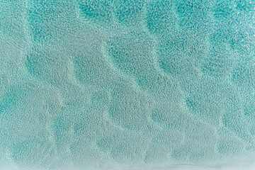 Aerial view of beautiful tropical turquoise ocean sea waters with shallow waves. Vibrant bright...