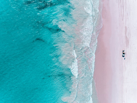 Aerial view of beautiful tropical turquoise ocean sea waters with shallow waves on pink beach. Vibrant bright sunny day in summer wallpaper. Sandy pink sand beach, Seascape background. Coastal