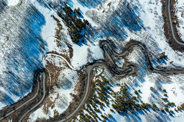 Aerial drone top view nature winter landscape serpentine highway automobile traffic hilly terrain natural valley. Slowly flight asphalt road turn passing cars through curve in mountainous area.