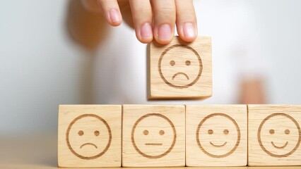 Hand choosing unhappy angry face from Emotion block. customer review, bad experience, negative feedback, satisfaction, survey, rating service, assessment, mood, world mental health day concepts