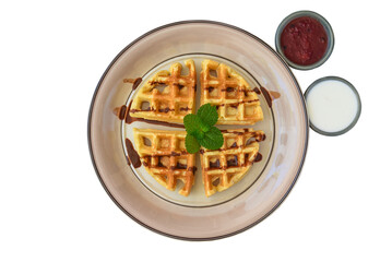 Belgium waffles with cinnamon on a plate with tropical topping and yogurt sauce