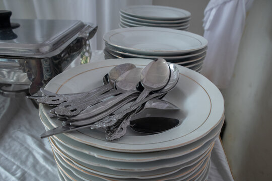selective focus to tablespoon on stack of white ceramic plates