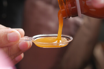 pour liquid medicine on top of spoon 