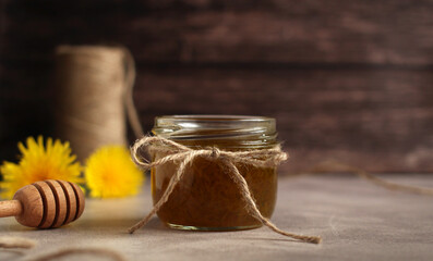 Dandelion flower jam in a glass jar on a wooden background