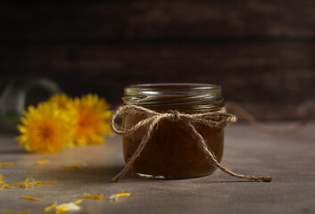 Dandelion flower jam in a glass jar on a wooden background