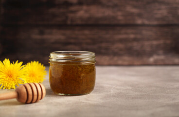 Dandelion flower jam in a glass jar on a wooden background