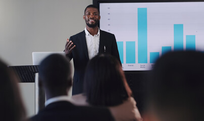 Black man, presentation and speaker with business graphs at seminar, workshop or training. Men and...