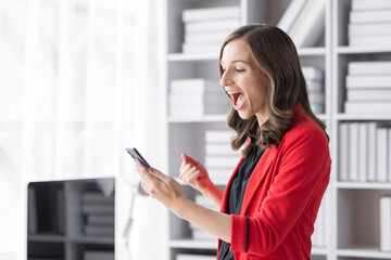 Excited happy Asian woman looking at the phone screen, celebrating an online win, overjoyed young asian female screaming with joy, isolated over a white blur background
