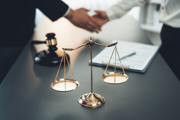 Focus gavel and justice scale on blur background of lawyer colleagues handshake after successful...