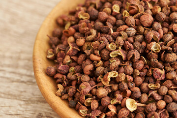 Sichuan peppercorn pepper spice seed in wood bowl on wooden table background. pile of Sichuan peppercorn pepper spice seed. Sichuan peppercorn pepper spice seed food background