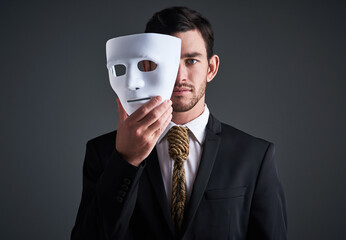 Two faces, holding mask and businessman portrait in a studio with serious face with secret and...