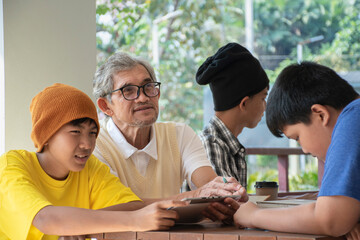 Group of young asian boys are sitting, preparing, choosing, discussing and consulting school subjects with their senior teacher, soft and selective focus on left boy, back to school concept.