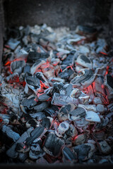 BBQ grill with glowing and flaming hot charcoal briquettes, close-up