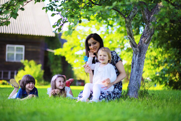 Obraz premium Young large family on a summer morning walk. Beautiful mother with children is playing in the park.