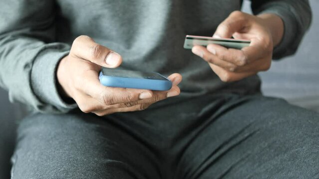 young man putting credit card detail on smart phone 