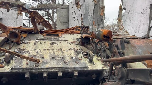 Rusty and broken side of tank with torn off turret Infantry fighting vehicle stands in house destroyed by artillery shells during war in ukraine