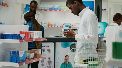 Young adult looking at packs of vitamins in drugstore, checking pharmaceutical products from racks....