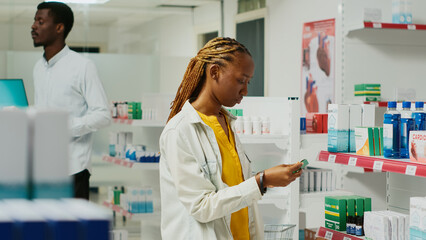 Female customer analyzing medical products in retail store, looking for pharmaceutics and healthcare drugs in pharmacy shop. Young woman checking packages of pills and medicine.