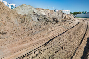 Open sand pit, for sand extraction during construction. The texture of sand and traces of the tread of large cars. Sand for construction work. Storage of sand at the construction site.