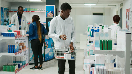 Young customer checking packs of medicine on shelves, looking to buy supplements and healthcare...