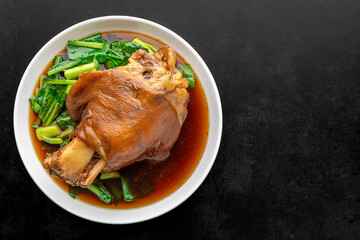 Kha Moo Pa Lo, Thai food, brown Chinese stewed pork leg in sweet brown sauce on dark tone texture background with copy space for text, top view shot